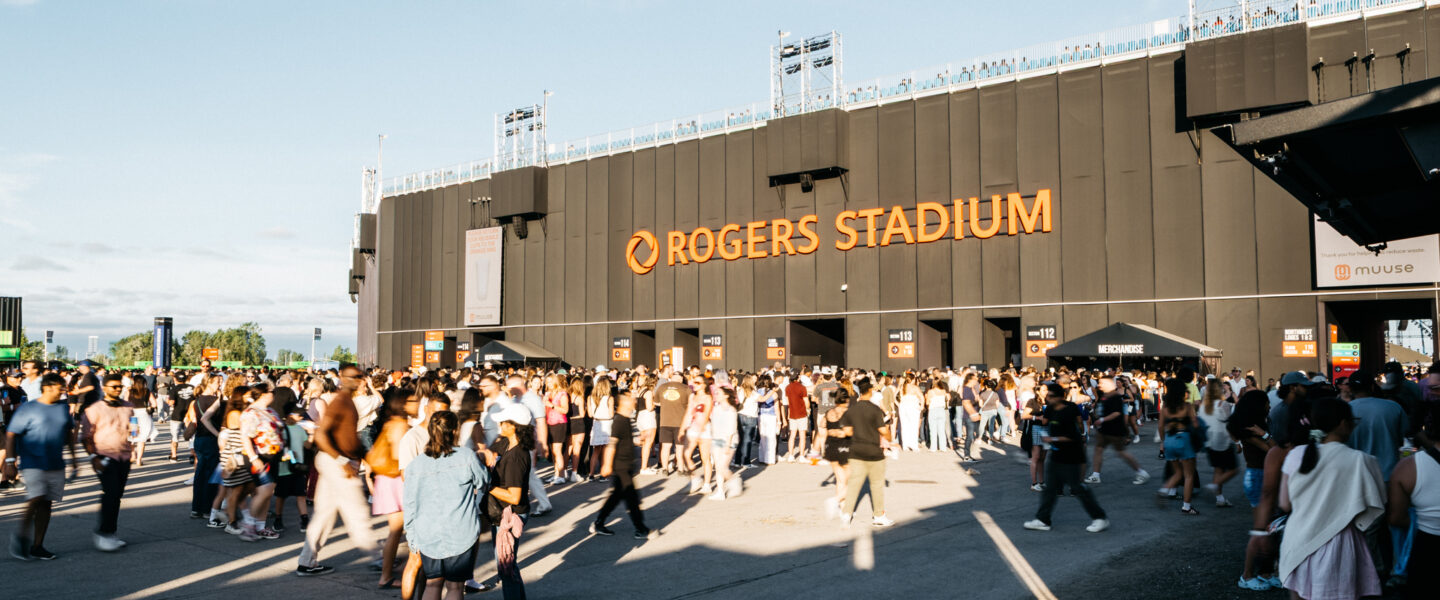 Concertgoers arriving at Live Nation Rogers Stadium 2025 with busy fan plaza and stadium branding