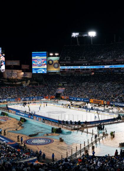 NHL Stadium Series 2026 Tampa at Raymond James Stadium with outdoor rink, Lightning and Bruins branding, beach-style installations, and sold-out crowd at night